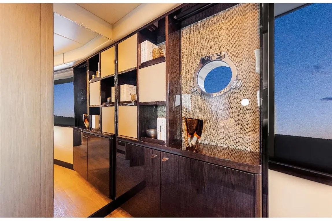 Stylish interior hallway featuring dark wood cabinets, decorative items, and a circular mirror with sunset view through windows.